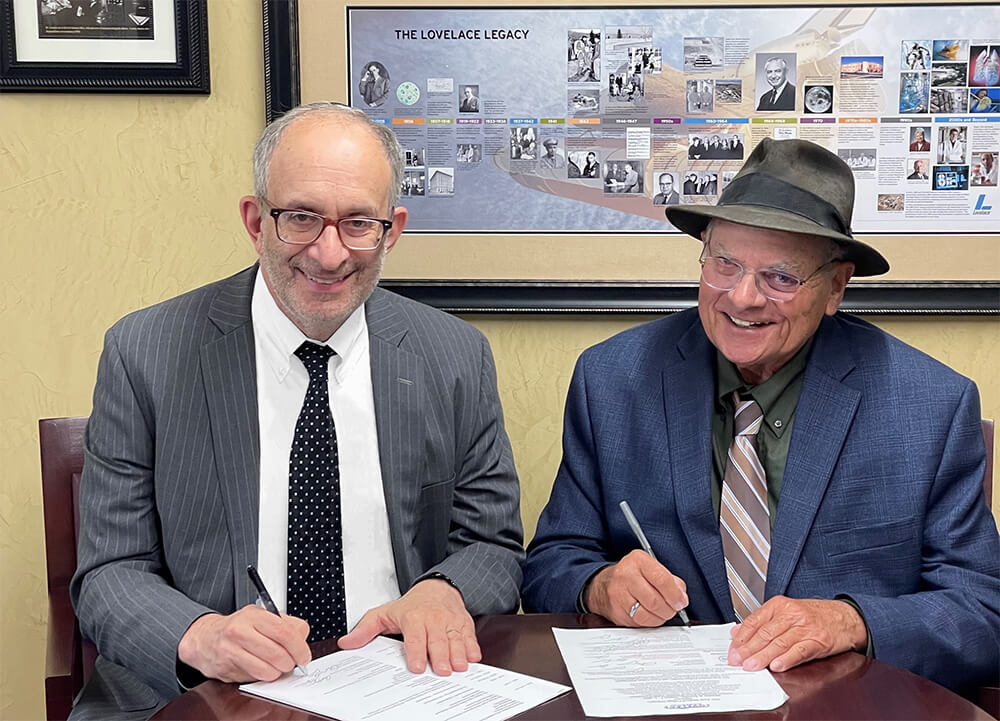 Touro President Dr Alan Kadish sitting at table signing documents with Lovelace Institute\'s President and CEO Dr Robert Rubin 