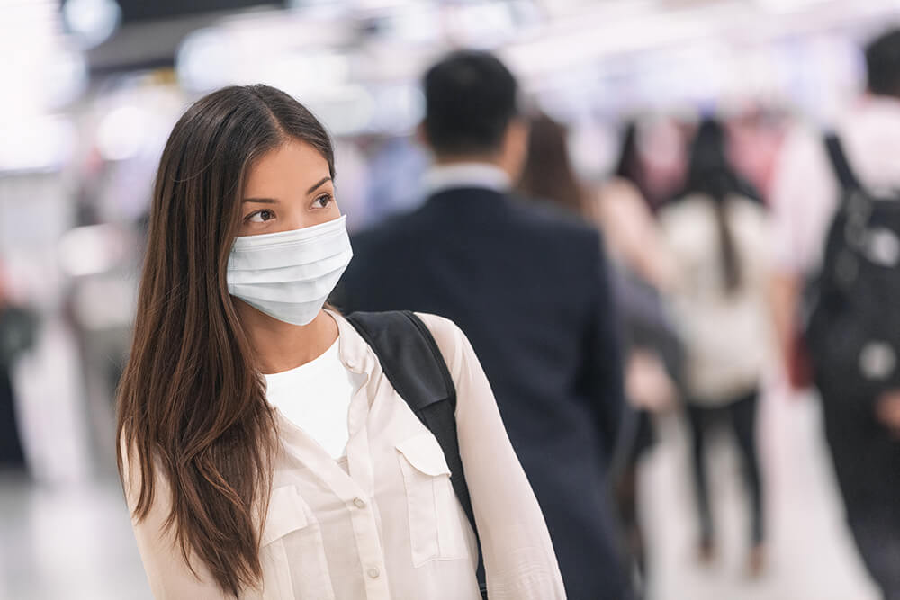 teen girl with mask outside on street with people walking in background