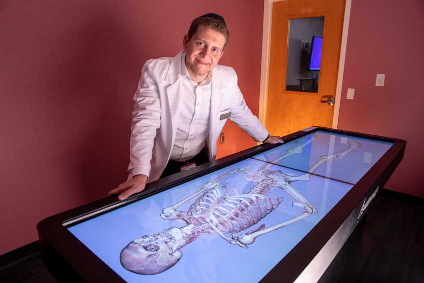Jacob Fliegelman posing with anatomage table in an NYMC facility