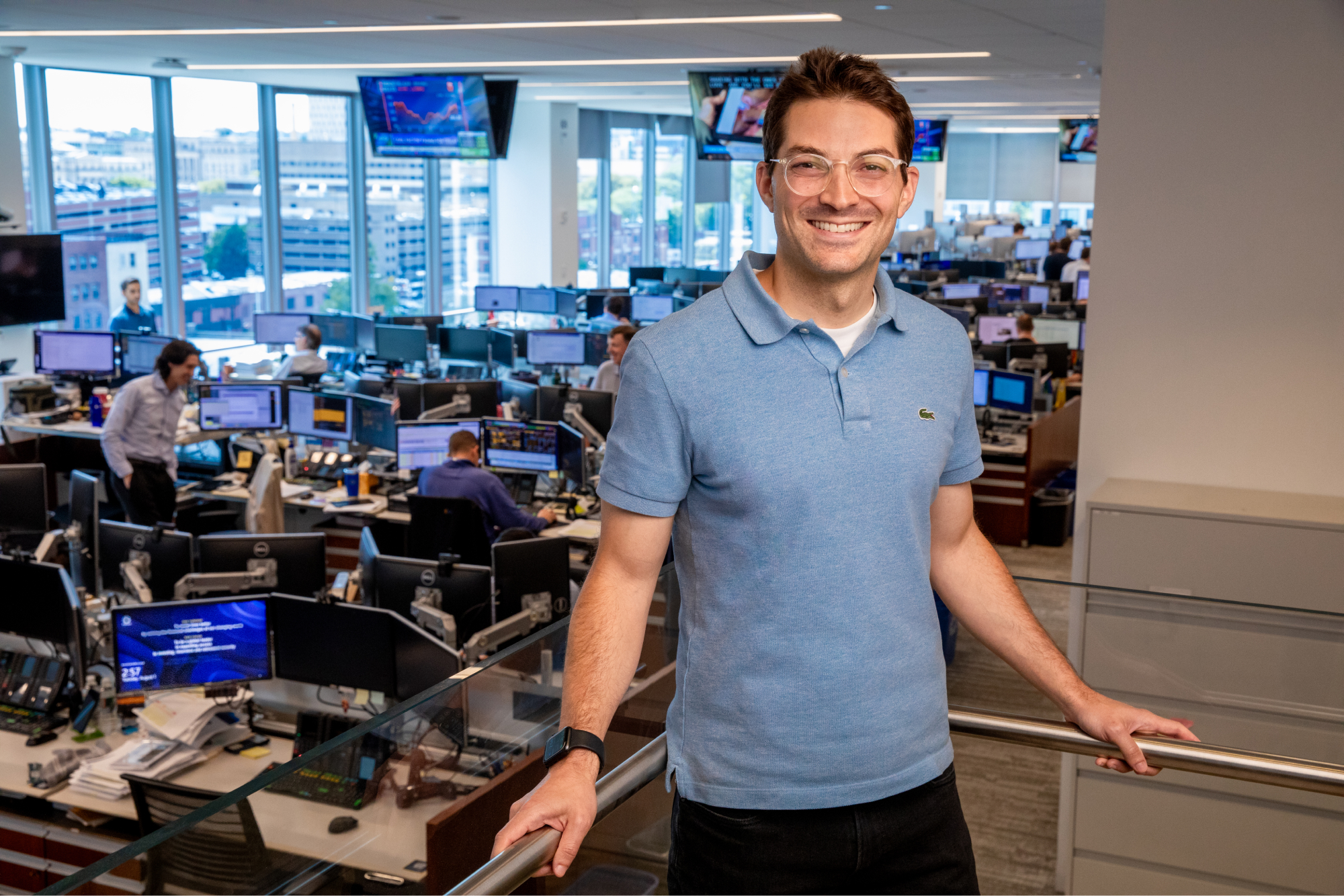 Jason Appleson posing at workplace with computers in back