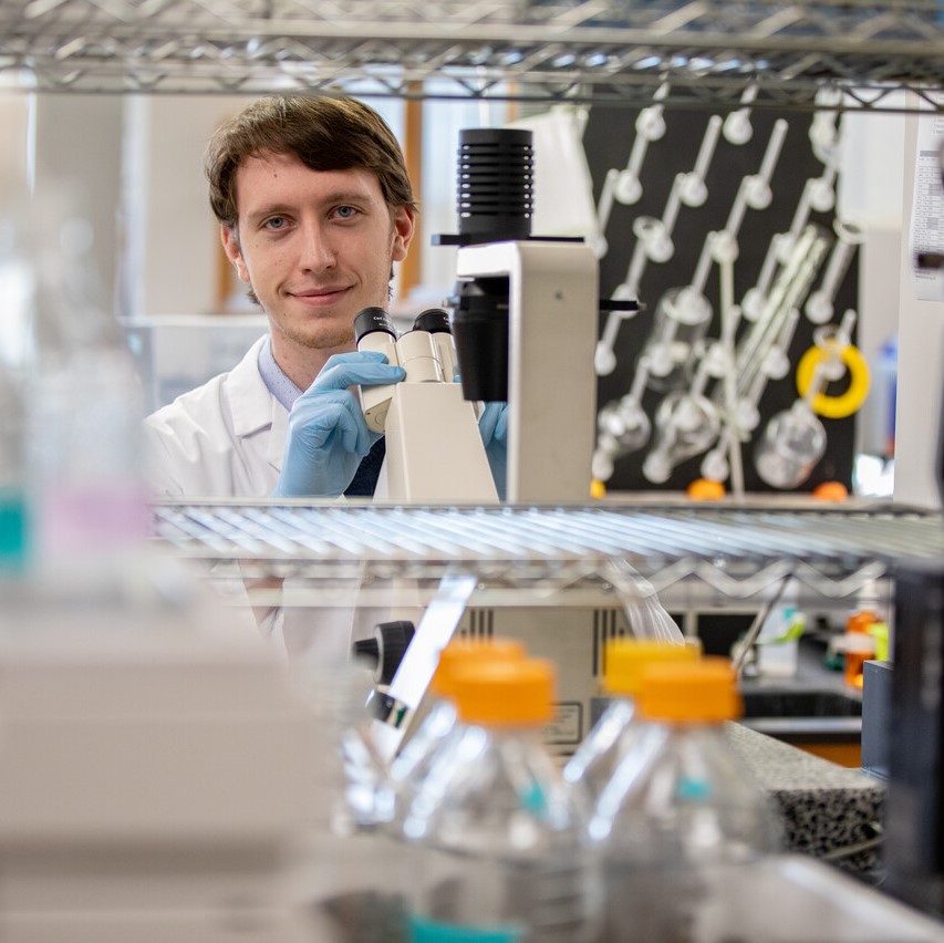 Dylan Kraus in lab with microscope