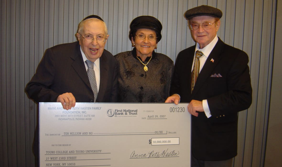 Bernard Lander with Anna Ruth and Mark Hasten, holding a blowup of the check the Hastens gave to Touro